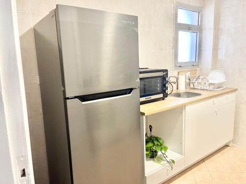- un réfrigérateur en acier inoxydable dans une cuisine à côté d'un four micro-ondes dans l'établissement Madinaty Luxury Elite Apartment, au Caire