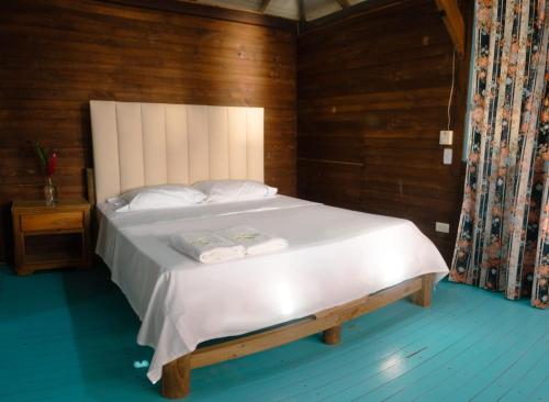 a bedroom with a large white bed with wooden walls at Hotel Bahía Aguacate in Capurganá