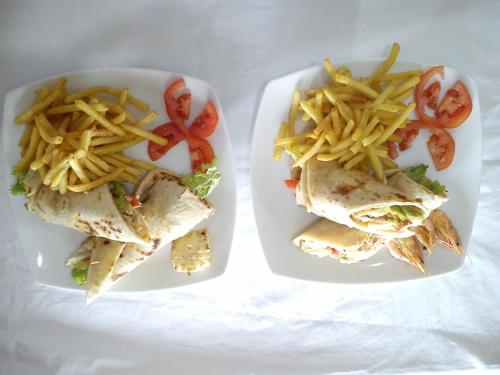 two plates of food with a sandwich and french fries at Dolphin Village in Kalpitiya