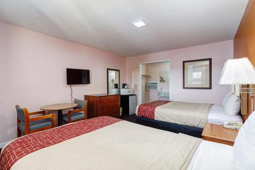 a hotel room with two beds and a desk at Regency Inn in Fayetteville