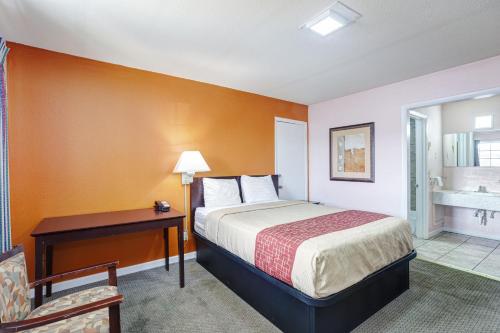 a hotel room with a bed and a desk and a bathroom at Regency Inn in Fayetteville