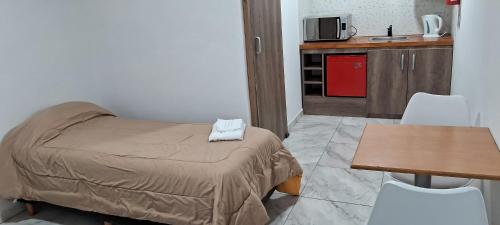 een kleine kamer met een bed en een tafel en stoelen bij El viejo LEPI Aparts in El Calafate