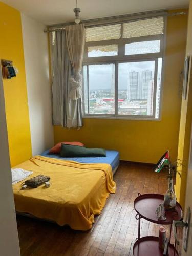 a bedroom with a bed and a window and a table at Veja o mar no silêncio do centro! Hospede-se no quarto in Recife