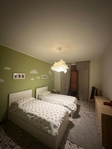 two beds in a bedroom with a chandelier at CASA ERT in Caserta