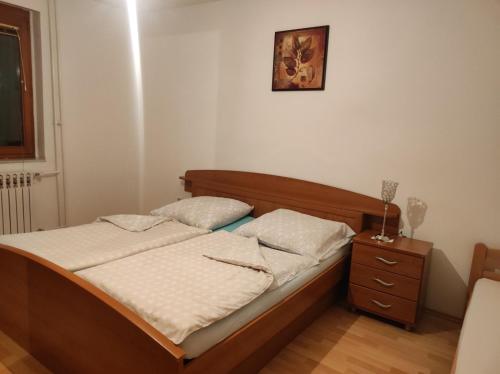 a bedroom with a bed with a wooden frame and a nightstand at Kerkira Apartment Pale in Pale