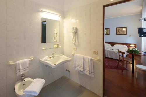 a bathroom with a sink and a mirror and a bed at Hotel Mariani in Iesi