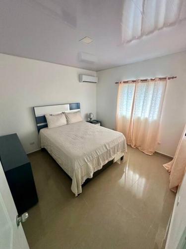een witte slaapkamer met een bed en een raam bij González Place in San Felipe de Puerto Plata