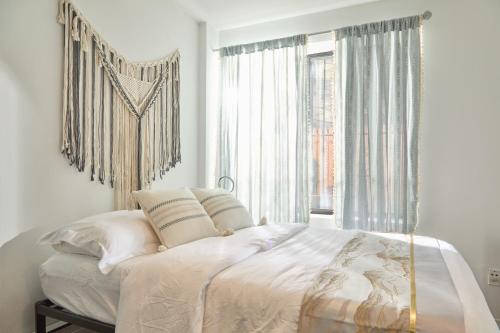 1 dormitorio con cama grande con sábanas blancas y ventana grande en American Dream Guest House, en Nueva York