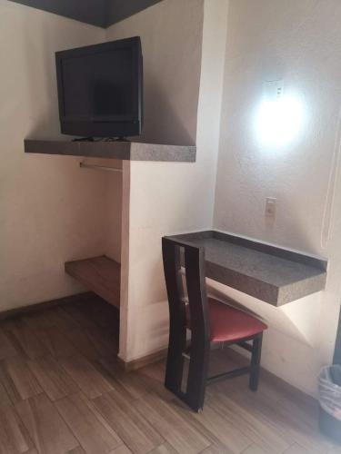 a room with a tv and a chair and a table at Hotel JA CENTRO Guadalajara in Guadalajara