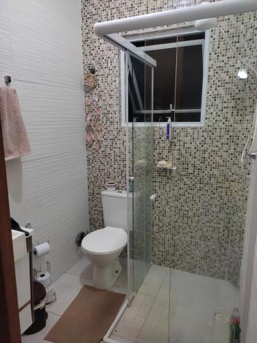 uma casa de banho com um WC e uma cabina de duche em vidro. em Cantinho da Lu em apt inteiro 800 mt da praia em Bertioga