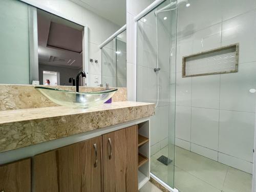 ein Bad mit einem Waschbecken und einer Glasdusche in der Unterkunft Apartamento Térreo Charmoso in Cabo Frio