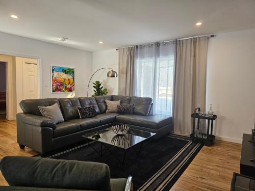 a living room with a leather couch and a table at Residence Orleans (inground pool) in Sainte-Petronille