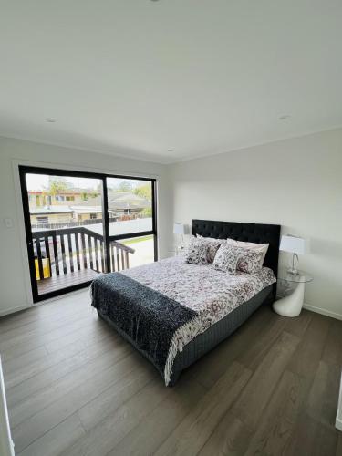 a white bedroom with a bed and a balcony at Matuhi Deluxe studio with kitchenette in Auckland