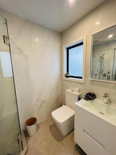 a white bathroom with a toilet and a sink at Matuhi Deluxe studio with kitchenette in Auckland