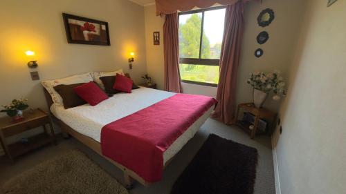 a bedroom with a bed with a red blanket and a window at Ilimay Las Cruces in Las Cruces
