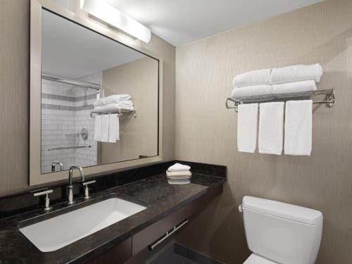 a bathroom with a sink and a mirror and a toilet at Holiday Inn Calgary Airport, an IHG Hotel in Calgary
