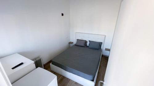 um pequeno quarto branco com uma cama e uma cadeira em VHostel em Guimarães
