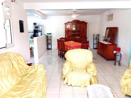 ein Wohnzimmer mit einem Sofa und einem Tisch in der Unterkunft Villa léïna, écotourisme jardin visite, chambre privée in Le Robert