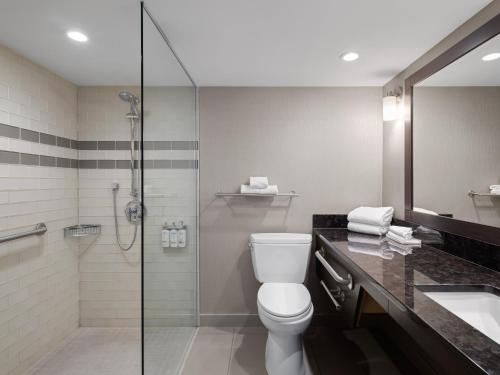 a bathroom with a shower and a toilet and a sink at Holiday Inn Calgary Airport by IHG in Calgary