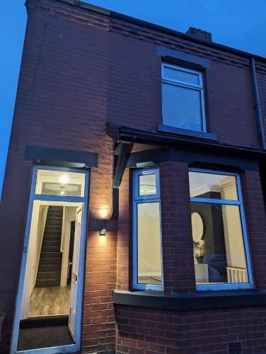 a brick house with two windows and a door at The road to Wigan Pier in Pemberton