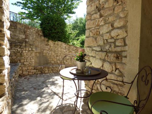 a table and chairs on a patio with a stone wall at Hôtel Lou Caleù restaurant le Rocher des Abeilles in Saint-Martin-de-Castillon
