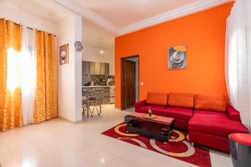sala de estar con sofá rojo y pared de color naranja en STUDIO BIAGUI 2, en Dakar
