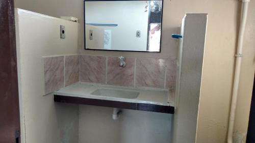 a bathroom with a sink and a mirror at Casas Aluguel Temporada Pousada Village Maçarico in Salinópolis