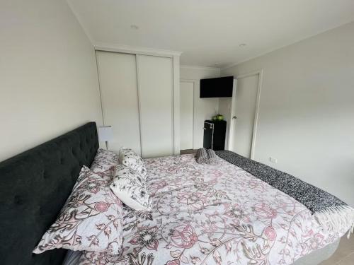 a bedroom with a bed with a floral bedspread and pillows at Matuhi Deluxe studio with kitchenette in Auckland