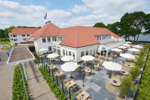 a patio area with tables, chairs and umbrellas at Fletcher Hotel-Restaurant ‘s-Hertogenbosch in Den Bosch