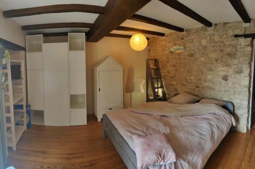 une chambre avec un lit et un mur en pierre dans l'établissement Maison familiale : charme & nature, à Senlis
