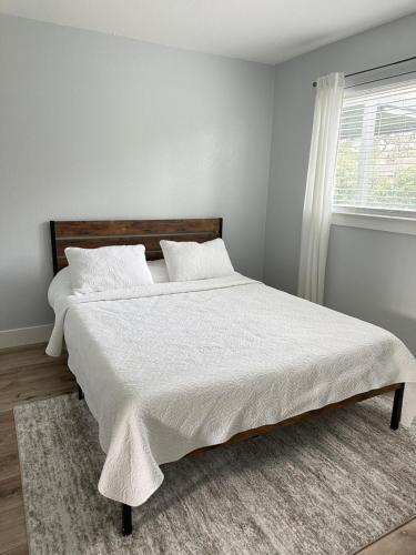 a bedroom with a bed with white sheets and a window at The Cozy Nook in Fair Oaks