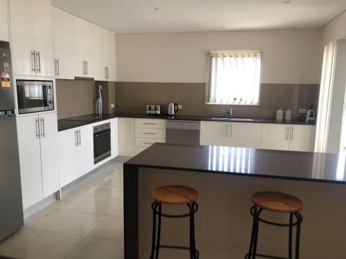 a kitchen with a counter and two bar stools at 4 @ Alta Mira - Soldiers Point in Soldiers Point