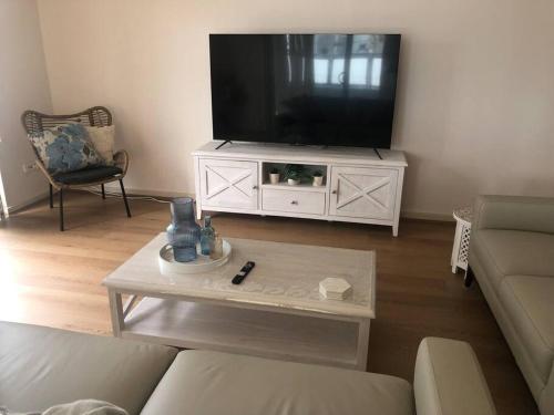 a living room with a flat screen tv on a white cabinet at 4 @ Alta Mira - Soldiers Point in Soldiers Point