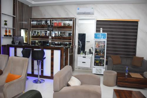 a living room with a bar with couches and chairs at Grand Seasons Hotel, Nnewichi in Nnewi
