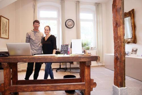 a man and woman standing next to a table with a laptop at Boutique Hotel Marielle in Bad Münstereifel