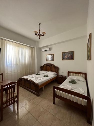 1 dormitorio con 2 camas y mesa en Hannas Hostel, en Berat
