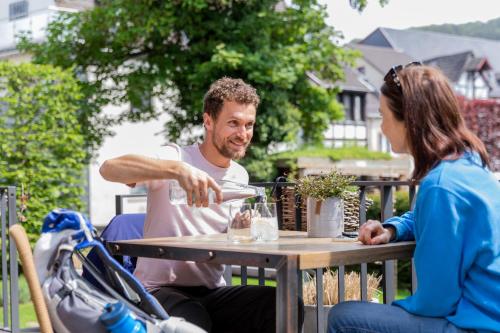 a man is sitting at a table with a woman at Boutique Hotel Marielle in Bad Münstereifel