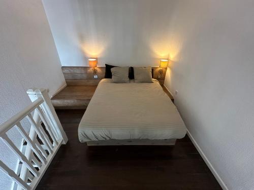 łóżko w pokoju z 2 lampami i schodami w obiekcie appartement sur la Marina st François w mieście Saint-François