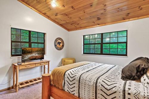 a bedroom with a bed and a desk and two windows at NEW HOT TUB! Secluded 3 Bed Cabin in Pigeon Forge in Pigeon Forge