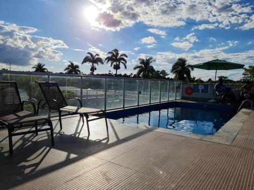 uma piscina com duas cadeiras e um guarda-sol em Hotel San Diego Pampulha - Flats Particular em Belo Horizonte