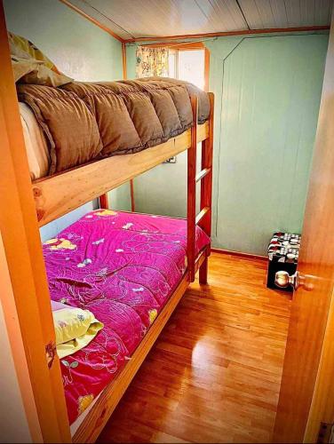 a room with two bunk beds and a wooden floor at Cabaña con estacionamiento privado in Llanquihue