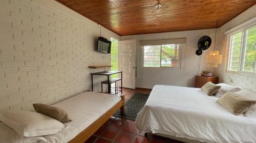 a bedroom with two beds and a brick wall at Finca Hotel Santana in Montenegro
