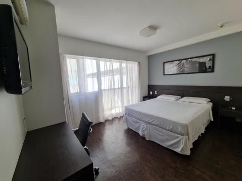 um quarto com uma cama e uma grande janela em Hotel San Diego Pampulha - Flats Particular em Belo Horizonte