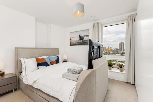 een slaapkamer met een bed, een televisie en een raam bij Khayat Homes - The Ferry - Two Bed in Londen