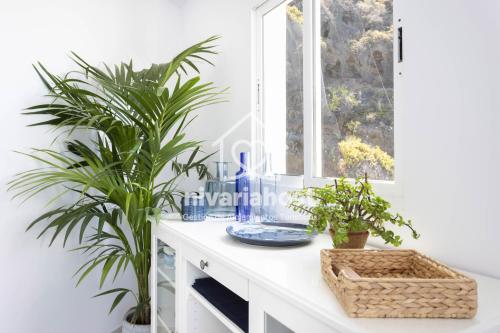 a white cabinet with two plants on it next to a window at Ocean View El Pris, by Nivariahost in El Pris