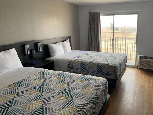 a hotel room with two beds and a balcony at Studio 6-Lincoln, NE - Airport in Lincoln