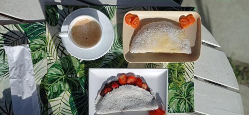 a table with two plates of food and a cup of coffee at Terra Nova Cabo Frio Front Beach in Cabo Frio