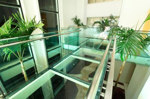 a glass walkway in a building with potted plants at Noroeste Atrium Platine Apartamento Completo in Brasilia