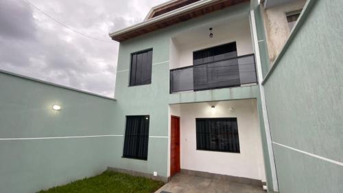 a white house with black windows and a red door at Triplex novo em Matinhos litoral Paraná in Matinhos