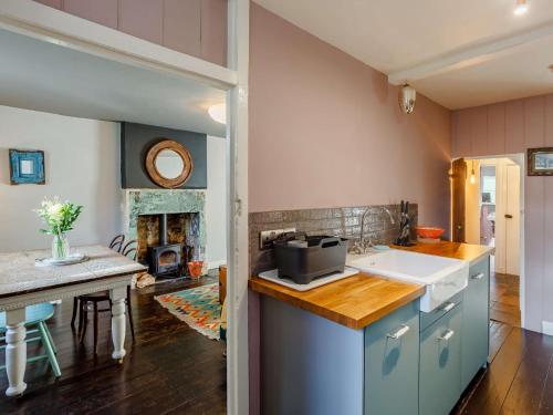 eine Küche mit einem Waschbecken, einem Tisch und einem Kamin in der Unterkunft 2 Bed in Bath 90431 in Wingfield